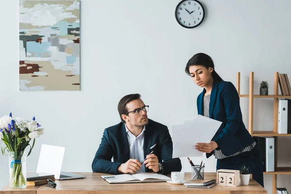 Compañeros de negocios mirando los papeles contractuales en la oficina - foto de stock