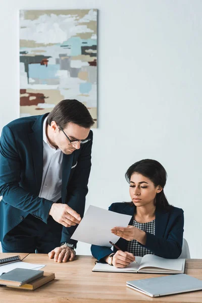 Empresaria mostrando papeles contractuales a su colega masculino en el cargo - foto de stock