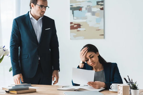 Homme d'affaires regardant femme d'affaires stressée avec des papiers dans les mains — Photo de stock