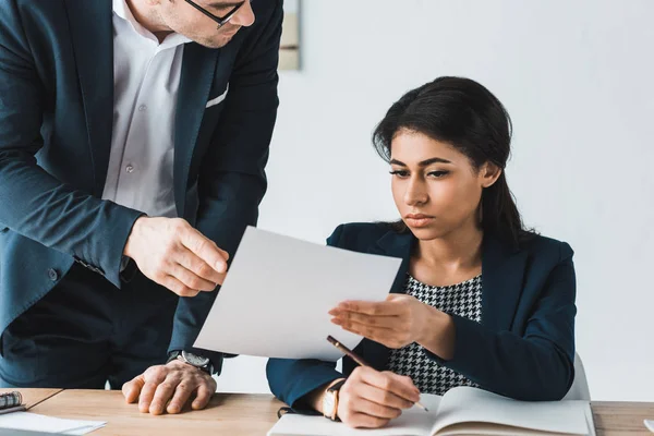 Empresário e mulher de negócios olhando para papéis contratuais no escritório — Fotografia de Stock