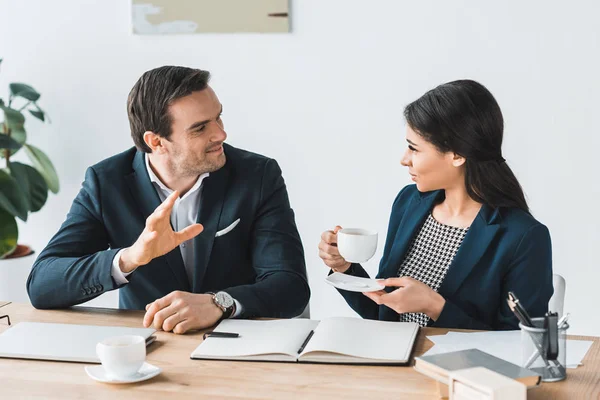 Empresario y empresaria teniendo una discusión sobre proyecto en oficina moderna - foto de stock