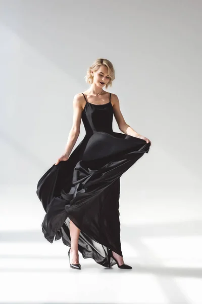 Hermosa chica elegante posando en vestido negro elegante, en gris - foto de stock