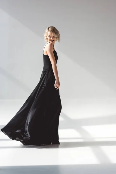 Mulher jovem na moda posando em vestido preto elegante, em cinza — Fotografia de Stock