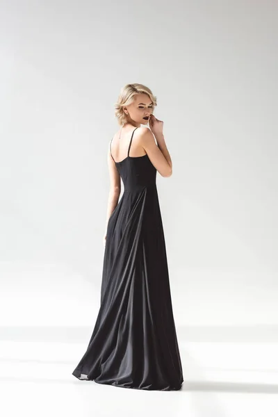 Beautiful girl posing in elegant black dress, on grey — Stock Photo
