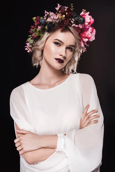 Atractiva chica rubia posando en vestido blanco y corona floral, aislada en negro - foto de stock