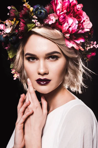 Portrait of attractive blonde girl posing in floral wreath, isolated on black — Stock Photo