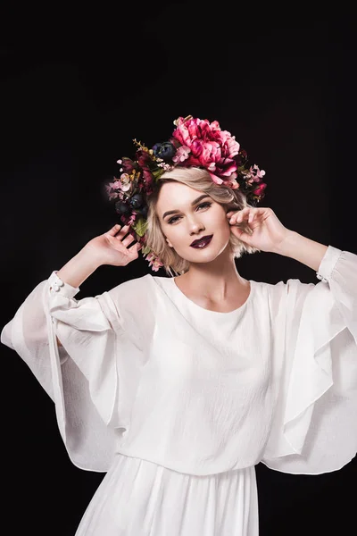 Atractiva mujer rubia posando en vestido blanco y corona floral, aislada en negro - foto de stock