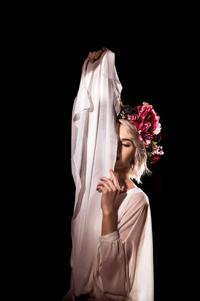 Ніжна дівчина позує в квітковому вінку з білою завісою, ізольована на чорному — стокове фото