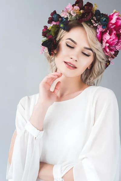 Smiling tender girl posing in floral wreath with beautiful butterfly, isolated on grey — Stock Photo