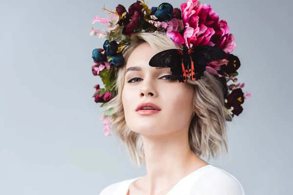 Beautiful girl posing in floral wreath with butterfly, isolated on grey — Stock Photo