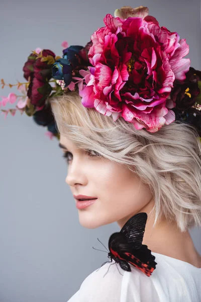 Portrait de fille élégante en couronne florale avec beau papillon à l'épaule, isolé sur gris — Photo de stock