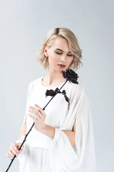 Beautiful blonde girl posing in white blouse with black rose, isolated on grey — Stock Photo