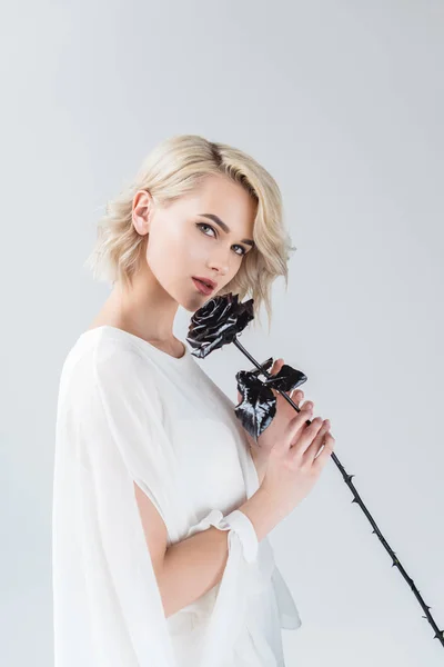 Привлекательная блондинка позирует в белой блузке с черной розой, изолированная на серой — стоковое фото