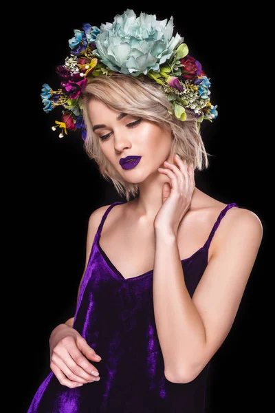 Atractivo modelo tierno posando en vestido púrpura y corona floral, aislado en negro - foto de stock