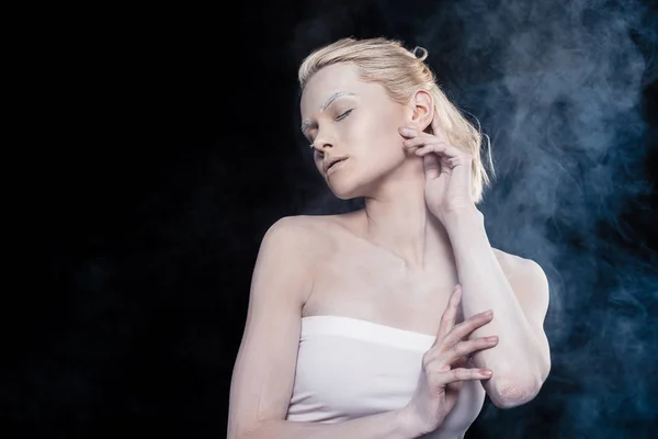 Atractiva chica tierna con los ojos cerrados y maquillaje blanco, aislado en negro con humo - foto de stock