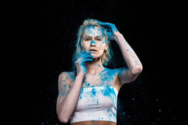 Young sensual woman posing in blue powder paint, isolated on black — Stock Photo