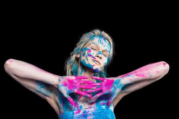 Blonde girl posing with closed eyes in pink and blue holi powder, isolated on black — Stock Photo