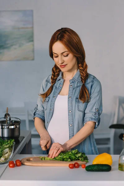 Attraente donna incinta che taglia verdure per insalata in cucina — Foto stock