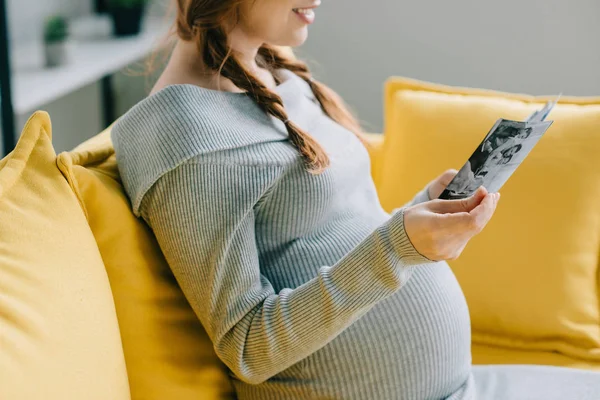 Imagem cortada de mulher grávida olhando para fotos na sala de estar — Fotografia de Stock