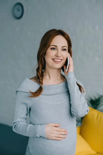 Attractive pregnant woman talking by smartphone at home — Stock Photo