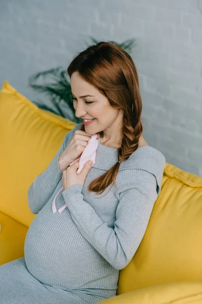 Seitenansicht attraktive schwangere Frau umarmt Baby-Hut im Wohnzimmer — Stockfoto
