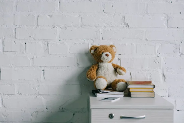 Oso de peluche, copybooks y libros sobre mesa auxiliar de madera - foto de stock