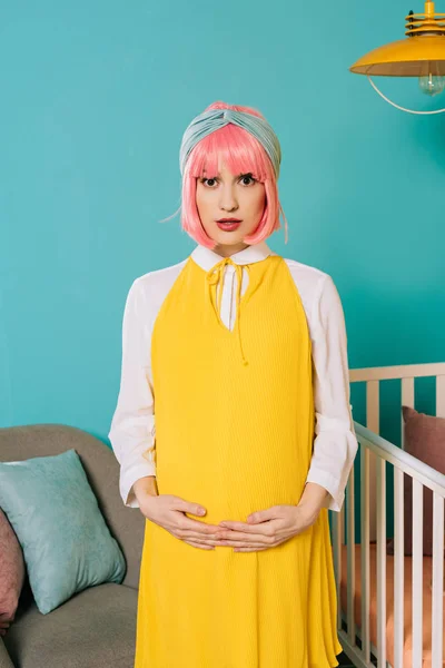 Incinta pin up donna con i capelli rosa toccando pancia nella stanza del bambino — Foto stock