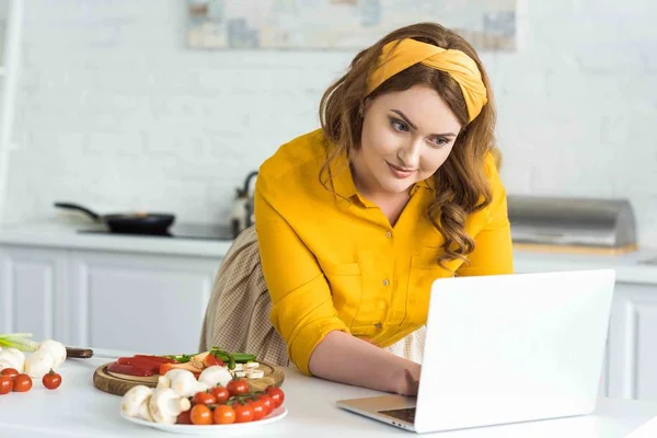 Hermosa mujer usando el ordenador portátil en la cocina - foto de stock