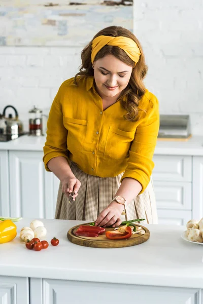 Bella donna che taglia verdure su tavola di legno in cucina — Foto stock