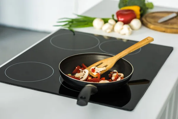 Frying pan with appetizing vegetables on electric stove in kitchen — Stock Photo