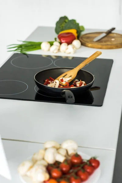 Frying pan with vegetables on electric stove in kitchen — Stock Photo