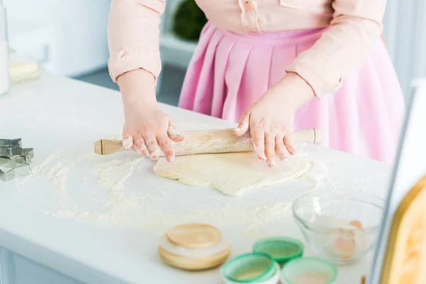 Cropped image of woman rolling dough with rolling pin in kitchen — Stock Photo