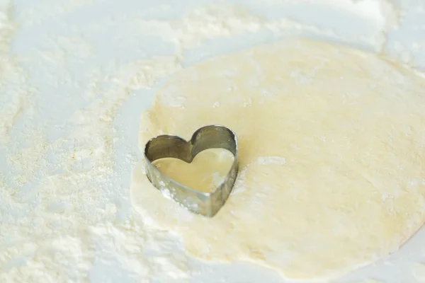 Un cortador de galletas en forma de corazón en la masa - foto de stock