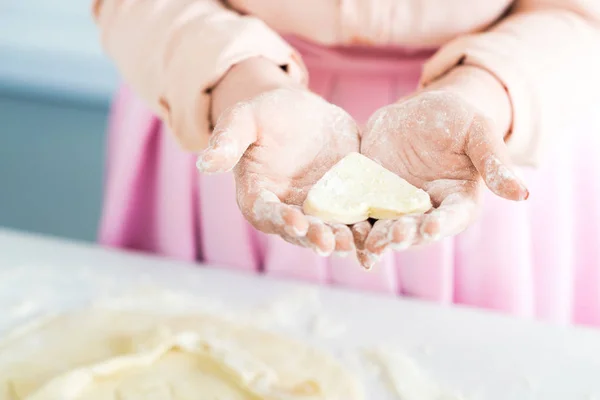Cropped image of woman holding raw heart shaped cookie in hands at kitchen — Stock Photo