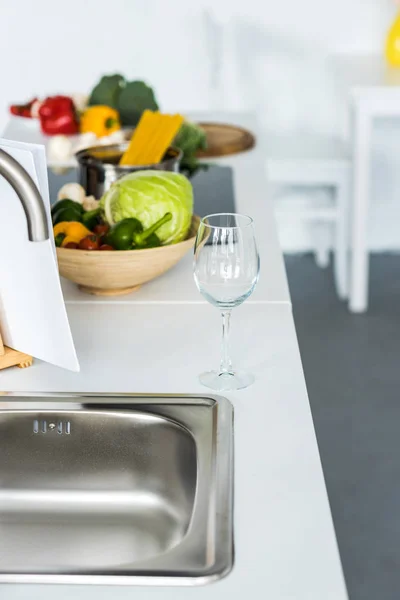 Empty wineglass and vegetables on kitchen counter — Stock Photo