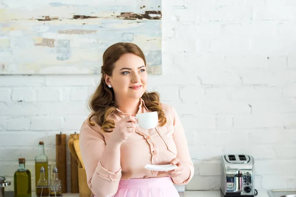 Schöne Frau trinkt Kaffee und schaut in der Küche weg — Stockfoto