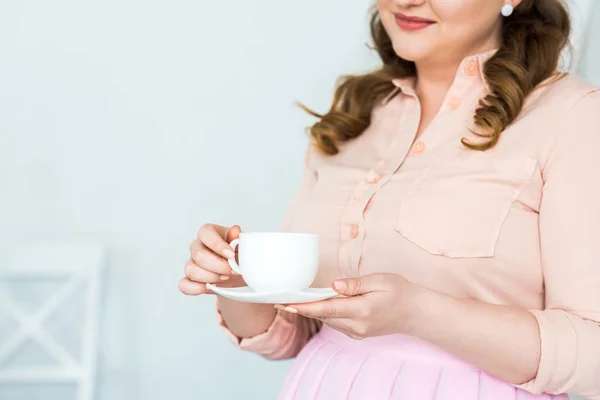 Обрезанный образ женщины, держащей чашку кофе на кухне — стоковое фото