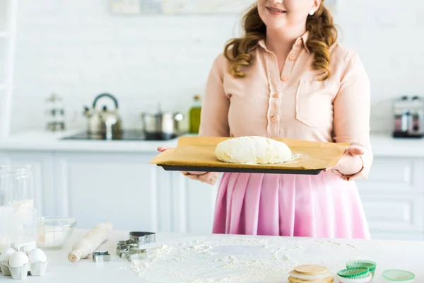 Imagem cortada de mulher segurando bandeja com massa para assar pão na cozinha — Fotografia de Stock