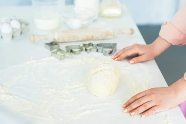 Imagen recortada de la mujer de pie cerca de la masa para hornear pan en la cocina - foto de stock