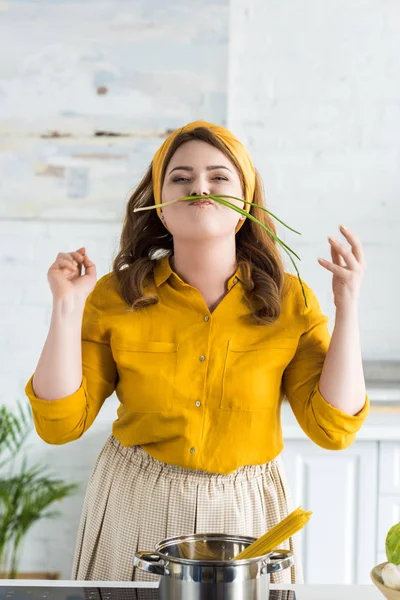 Bela mulher fazendo bigode com cebola verde na cozinha — Fotografia de Stock