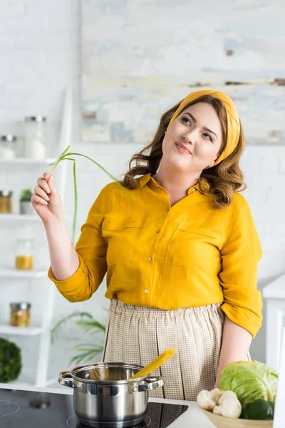 Chère belle femme tenant l'oignon vert dans la cuisine — Photo de stock