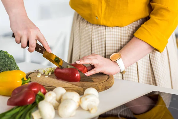 Imagem cortada de mulher cortando pimentão maduro na cozinha — Fotografia de Stock