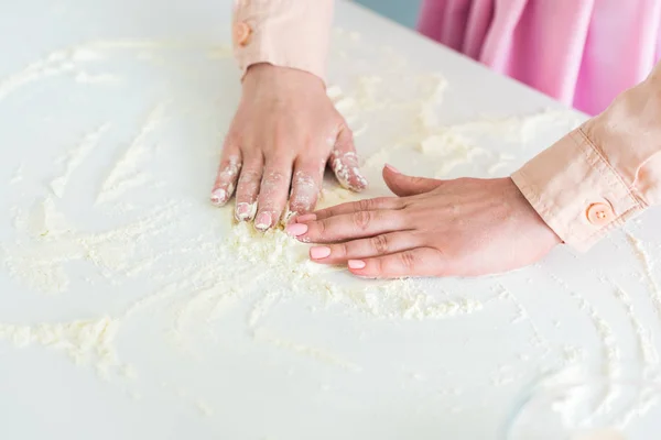 Imagen recortada de la mujer esparciendo harina en el mostrador de cocina - foto de stock