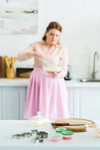 Hermosa mujer batiendo masa con cortadores de galletas en primer plano en la cocina - foto de stock