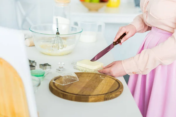 Immagine ritagliata di donna che taglia burro in cucina — Foto stock