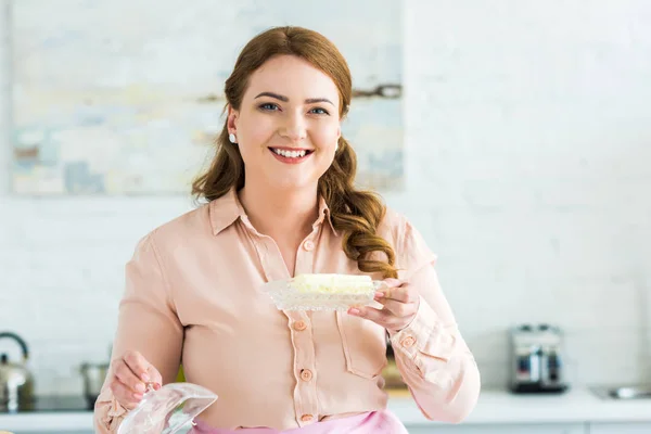 Sonriente hermosa mujer sosteniendo mantequilla en cocina - foto de stock