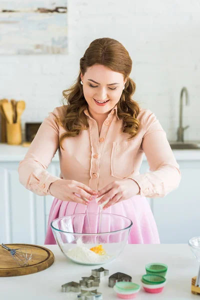 Belle femme ajoutant oeuf à la farine pour la pâte à la cuisine — Photo de stock