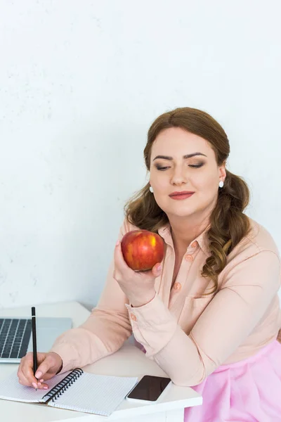 Hermosa mujer mirando manzana en la cocina - foto de stock