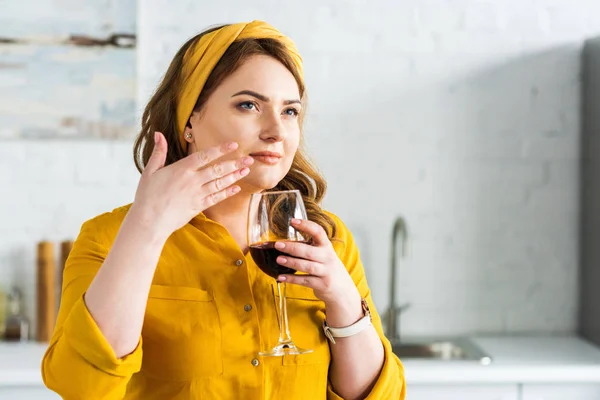 Bela mulher cheirando vinho tinto na cozinha — Fotografia de Stock