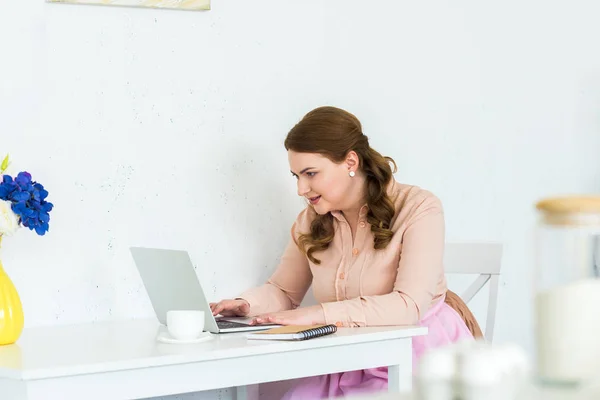 Mulher bonita usando laptop na mesa na cozinha — Fotografia de Stock